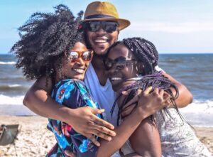 Home 7 Three friends enjoying a sunny day at the beach, embracing with smiles.